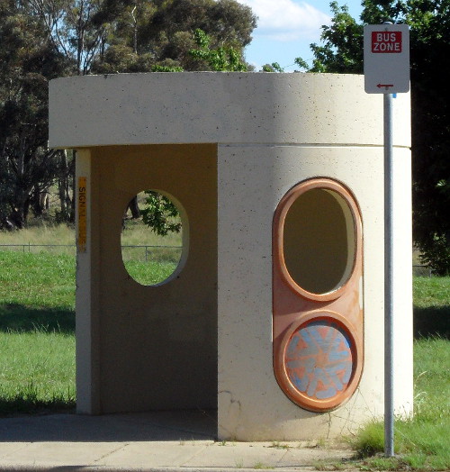 A concrete bus shelter without windowpanes due to vandalism
